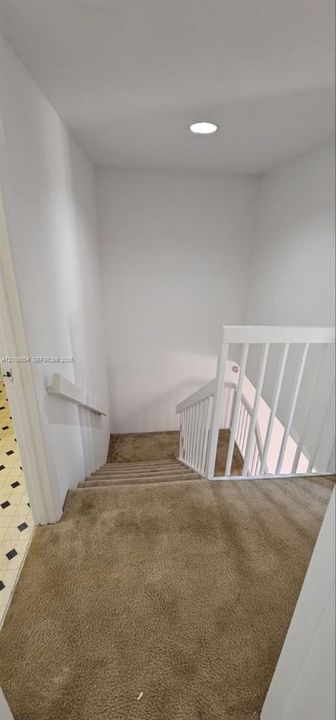 Staircase featuring wall-to-wall carpeting, white wooden balustrade, mounted handrail, and recessed ceiling lighting