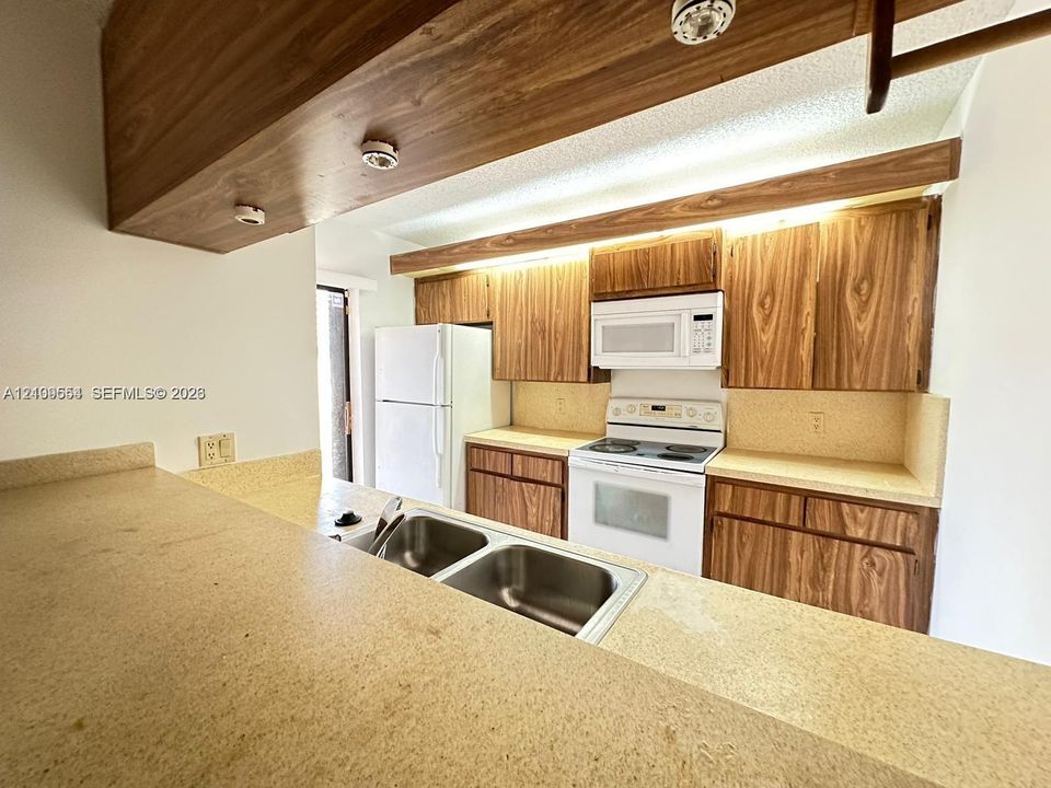 Kitchen featuring wood-grain cabinetry, solid surface countertops, a dual-basin stainless steel sink, and built-in appliances