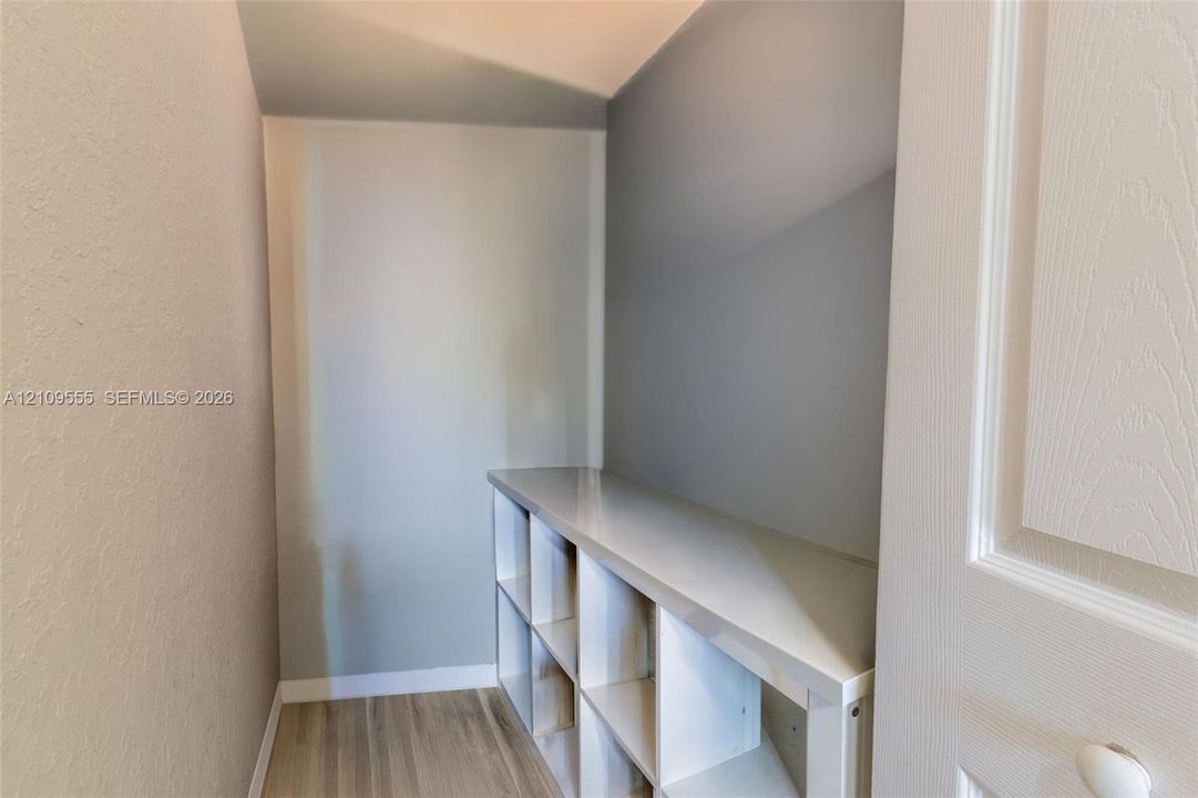 Built-in white cubby storage featuring a smooth countertop surface, wood-finish flooring, and a solid-core interior door