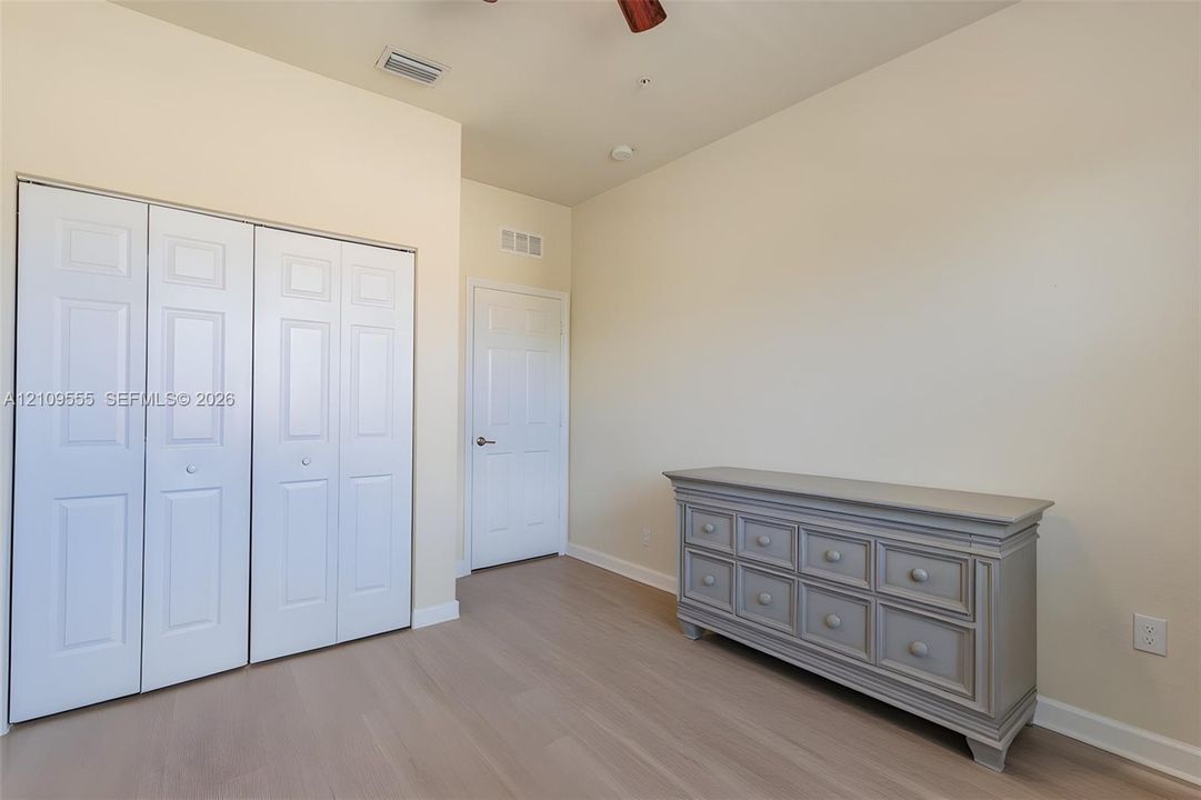 Room featuring wood-finish flooring, high ceilings, ceiling fan, and bi-fold closet doors