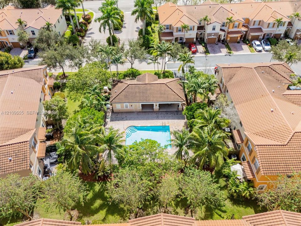 Aerial perspective of a detached property featuring a private swimming pool, concrete paver pool deck, covered patio, and mature landscaping