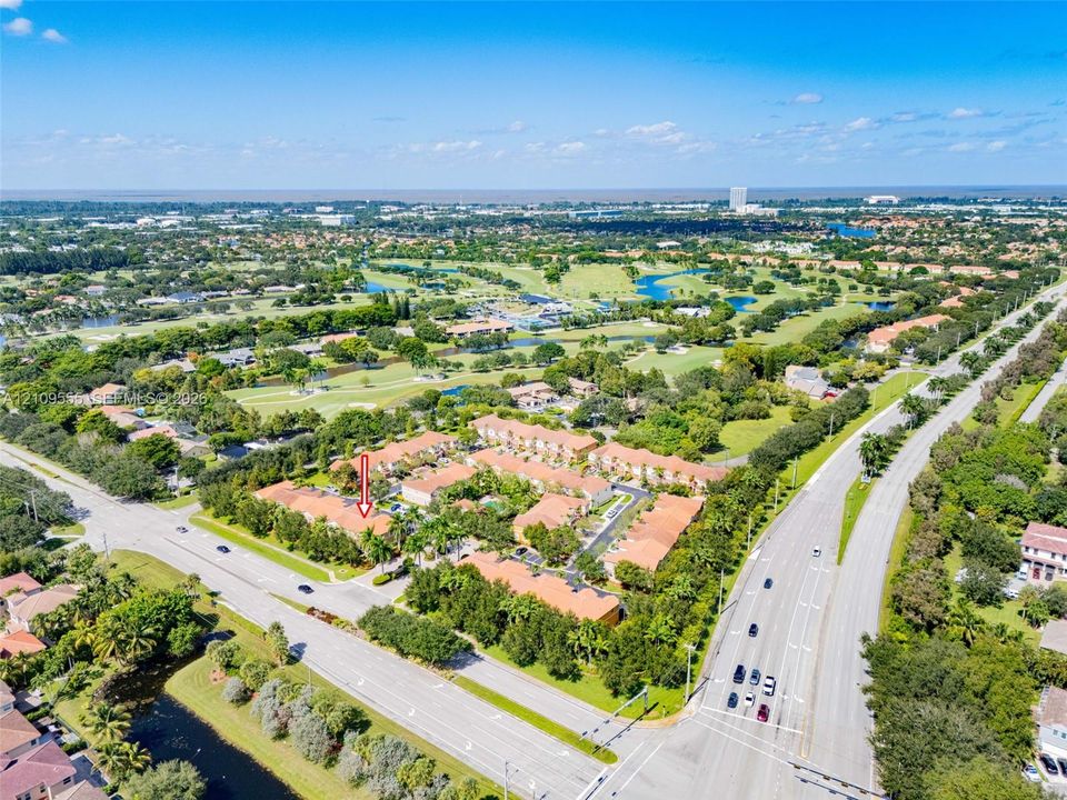 Aerial perspective of a multi-unit residential complex featuring terracotta-tiled roofs, mature landscaping, and proximity to a sprawling golf course