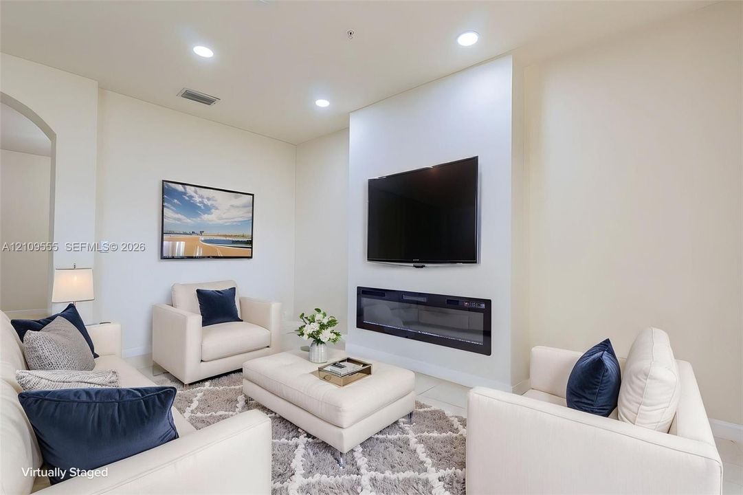 Wall-mounted electric fireplace with a minimalist hearth design, high ceilings, and recessed lighting