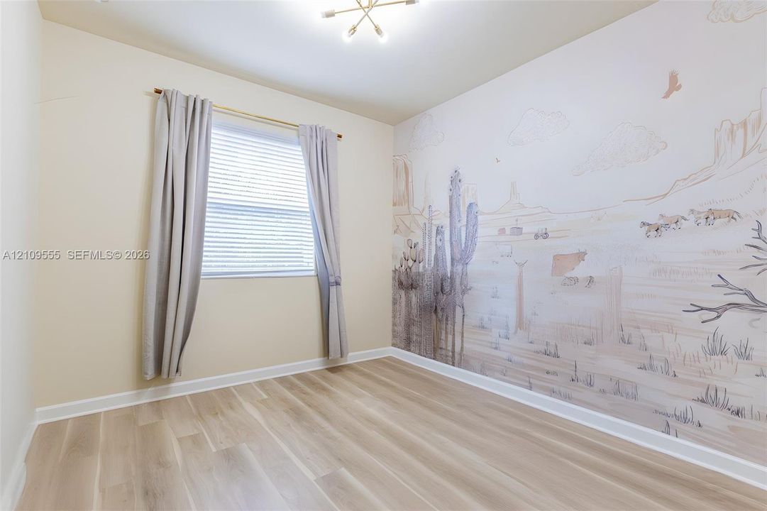 Neutral-toned wood-finish flooring, custom wall mural, horizontal slat blinds, and multi-arm geometric ceiling fixture