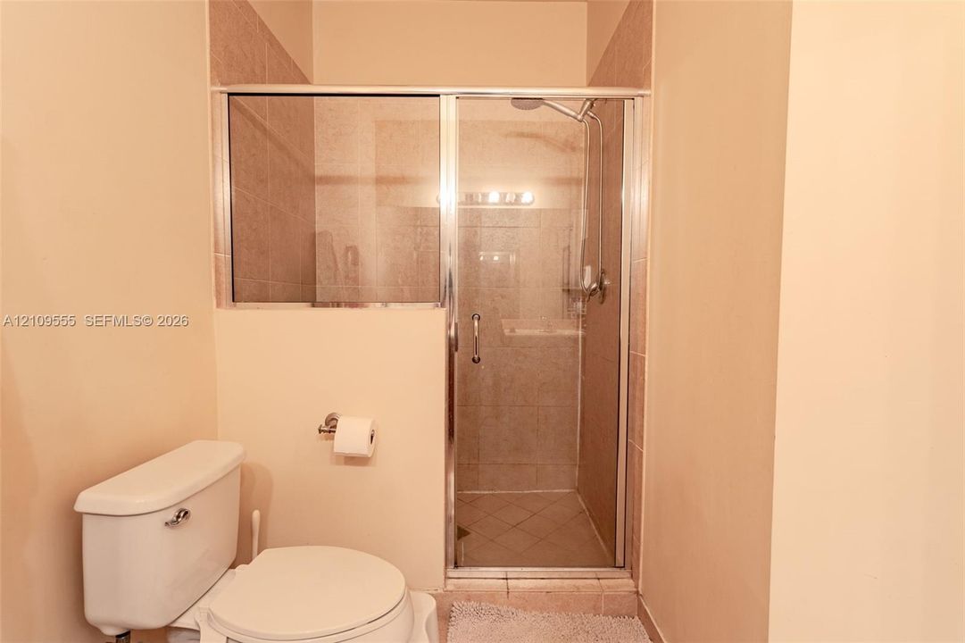Walk-in shower featuring glass enclosure, tiled surround, and polished metal fixtures