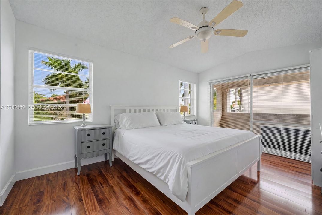 Wood-finish flooring, vaulted ceilings with a center fan, and large windows with horizontal blinds