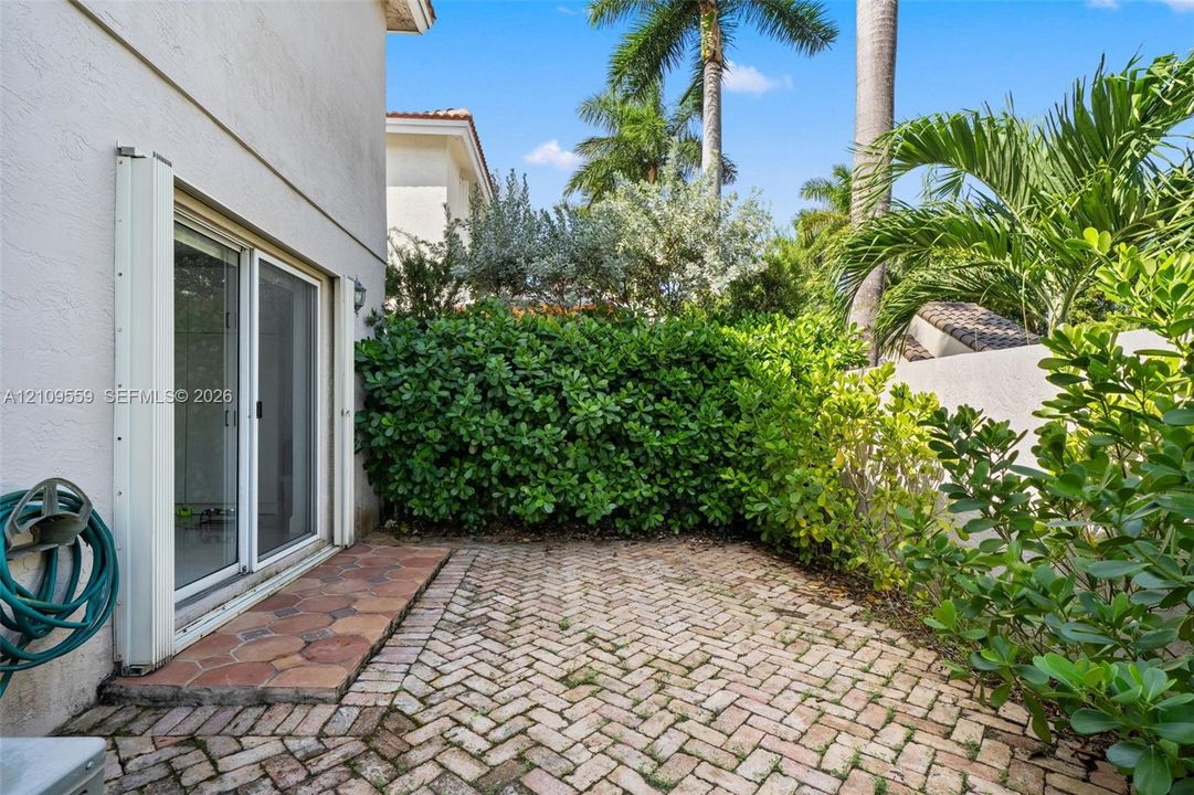 Private patio featuring herringbone-pattern brick paving, natural stone border accents, and established hedge landscaping