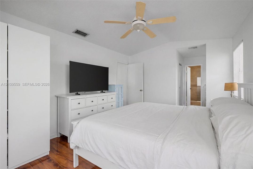 Vaulted ceilings, wood-finish flooring, and a ceiling fan with light fixture