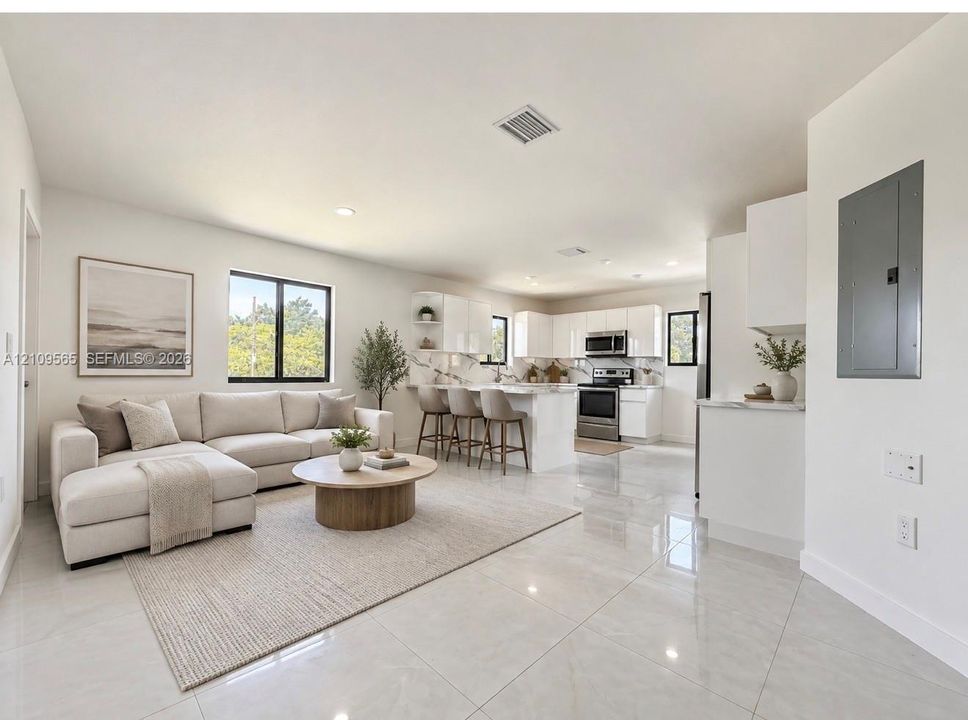 Open-concept living space featuring high-gloss cabinetry, stone-finish countertops, stainless steel appliances, and large-format tile flooring