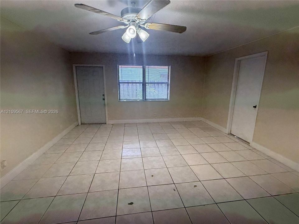 Ceramic tile flooring, neutral wall tones, multi-pane window, and a central ceiling fan with integrated lighting