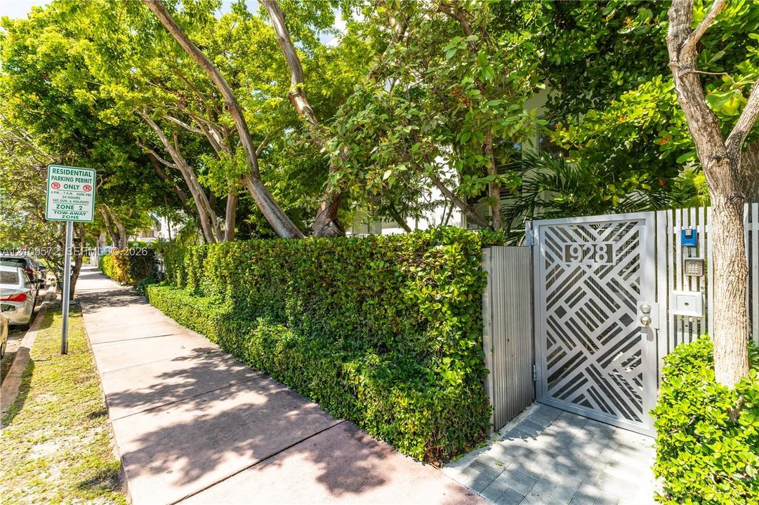 Geometric metal gate with integrated address signage, privacy hedging, and mature canopy trees