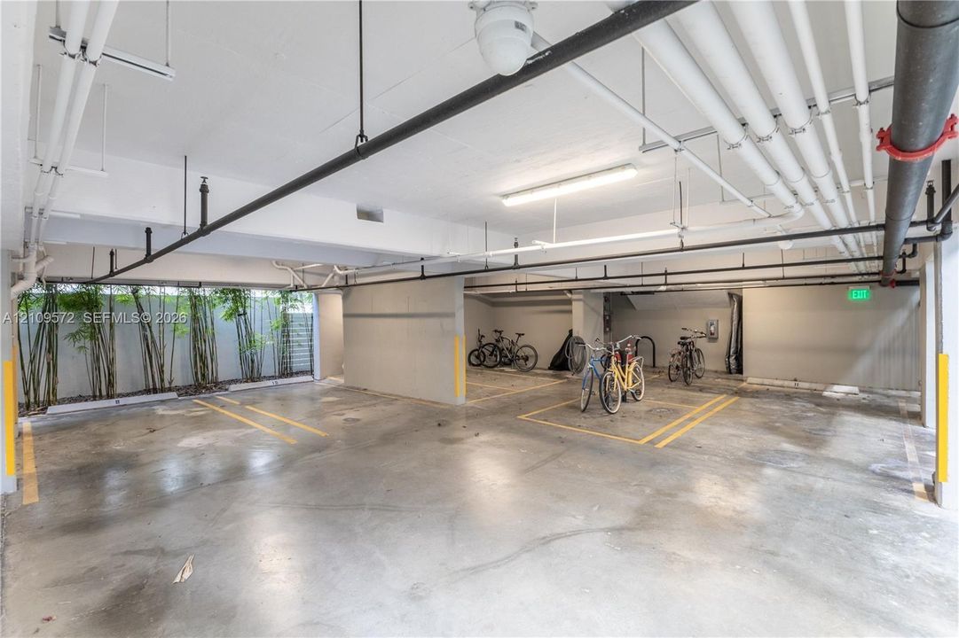 Covered parking area featuring concrete flooring, overhead linear lighting, and integrated greenery accents