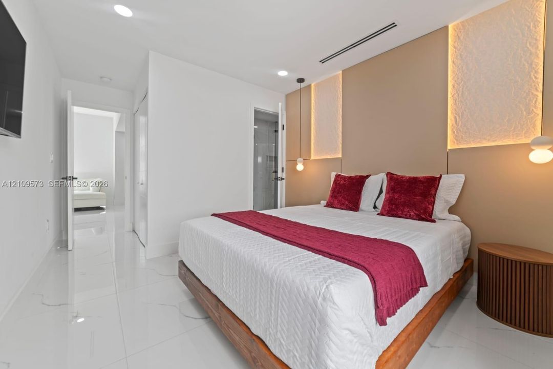 Polished stone flooring, custom wall paneling with integrated accent lighting, and dual suspended pendant lights