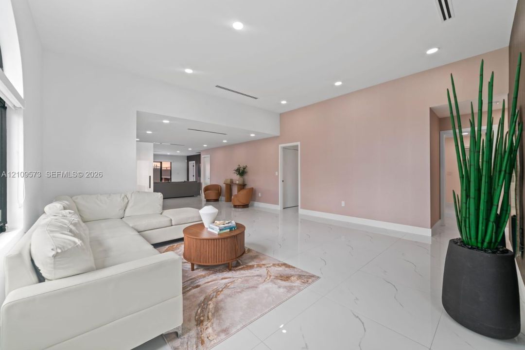 Open-concept interior featuring large-format polished tile flooring, high ceilings with recessed lighting, and a soft-toned accent wall