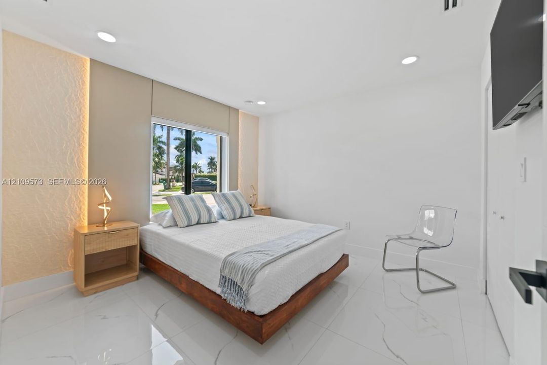 Large-format tile flooring with veining detail, recessed lighting, and a textured accent wall with integrated perimeter illumination