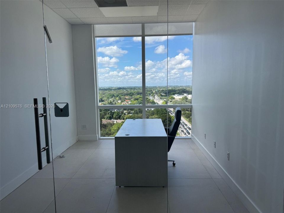 Floor-to-ceiling windows featuring panoramic exterior scenery, large-format tile flooring, and glass-paneled entry door with vertical metal hardware