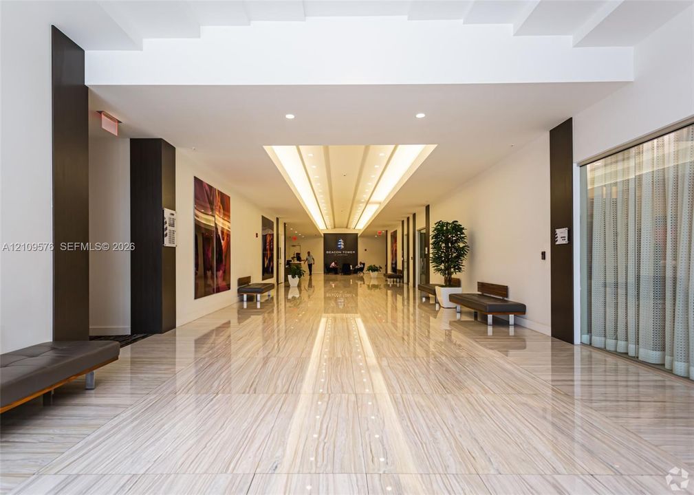 Grand lobby featuring polished stone flooring, recessed ceiling lighting, and dramatic dark architectural accents