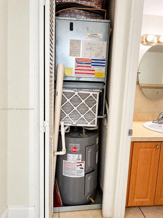 Mechanical closet containing a vertical air handler unit and a Rheem Performance electric water heater