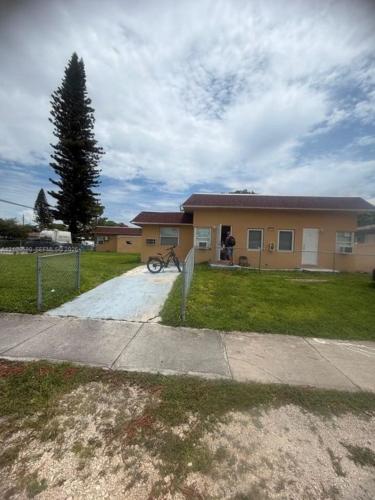 Single-story exterior featuring a stucco facade, medium-tone shingle roofing, and a concrete driveway