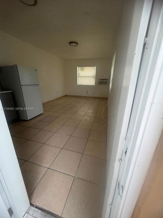 Ceramic tile flooring, white top-freezer refrigerator, and wall-mounted air conditioning unit