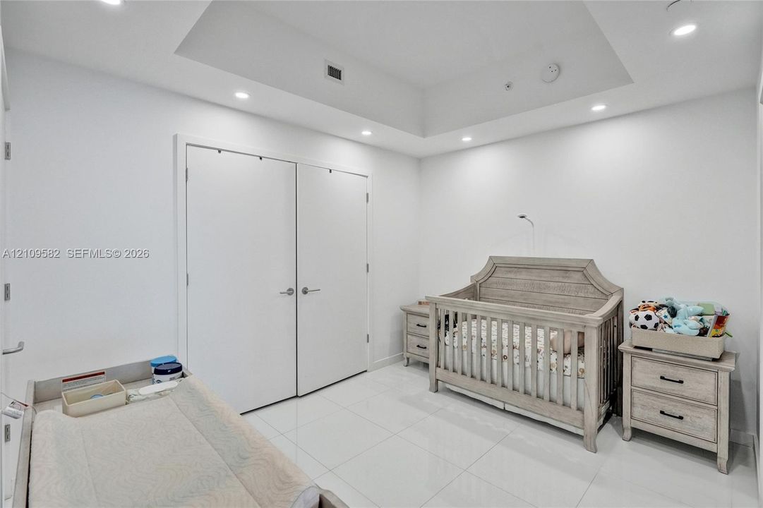 Interior space featuring high-gloss tile flooring, a recessed tray ceiling, integrated recessed lighting, and a double-door reach-in closet