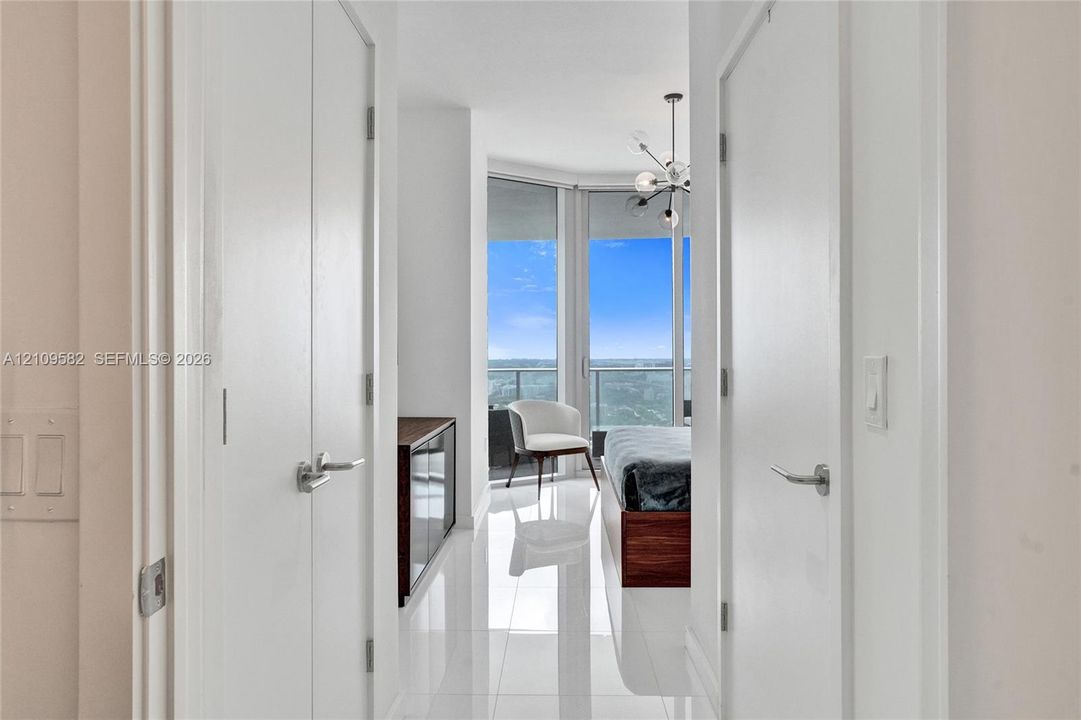Floor-to-ceiling windows, polished tile flooring, multi-arm chandelier, and double-closet configuration
