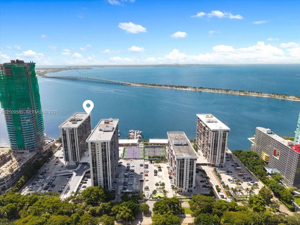 Waterfront high-rise complex featuring multiple tennis courts, a private dock