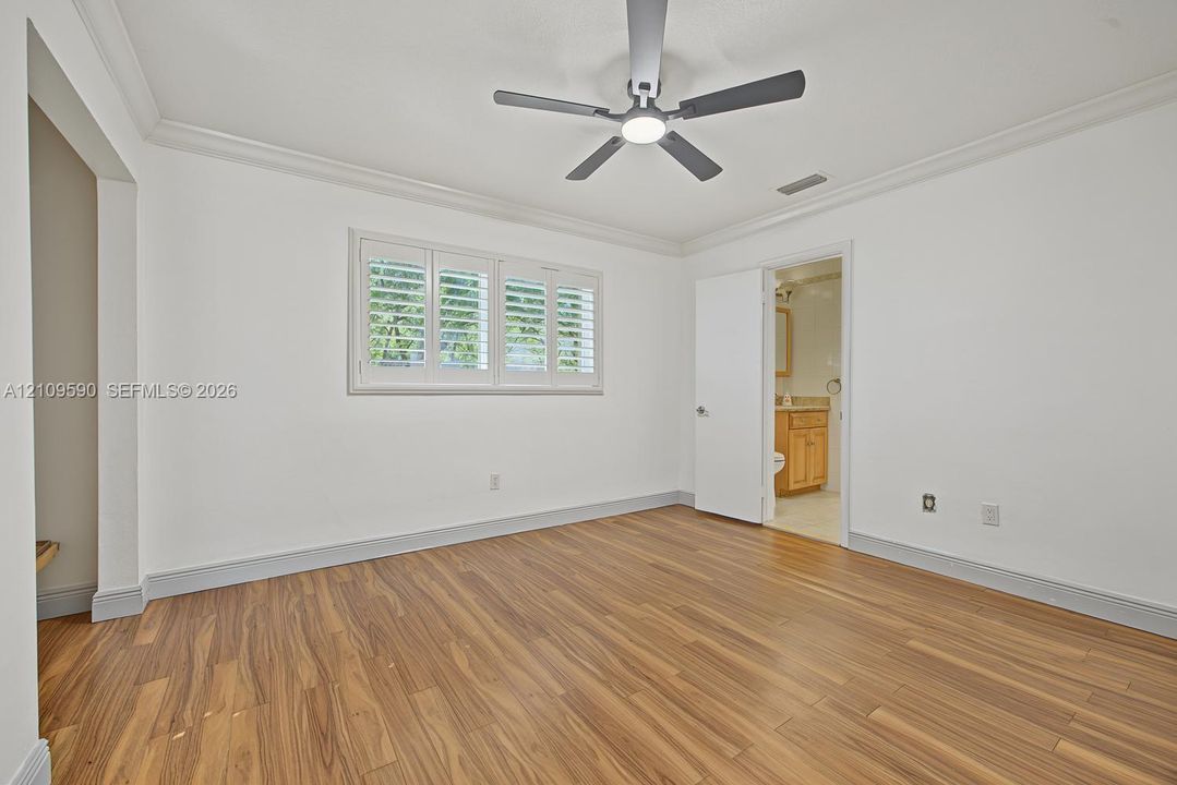 Bedroom 3 - Room featuring wood-finish flooring, crown molding, plantation shutters, and a central ceiling fan with integrated lighting