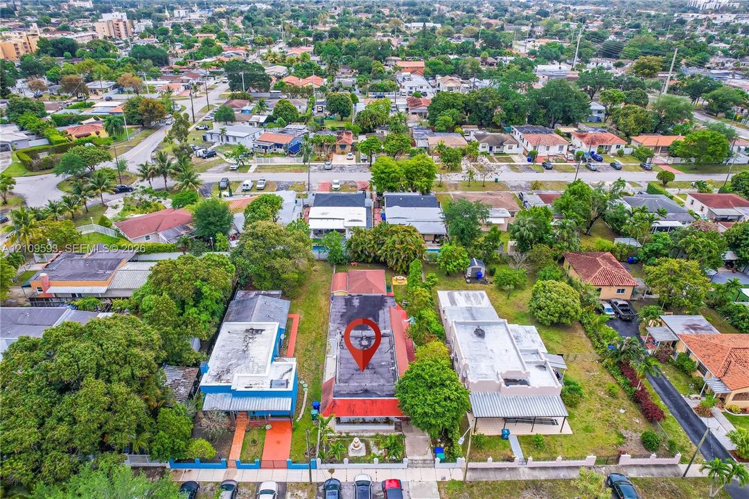 Aerial perspective of a detached residential property featuring a flat roof structure and mature trees