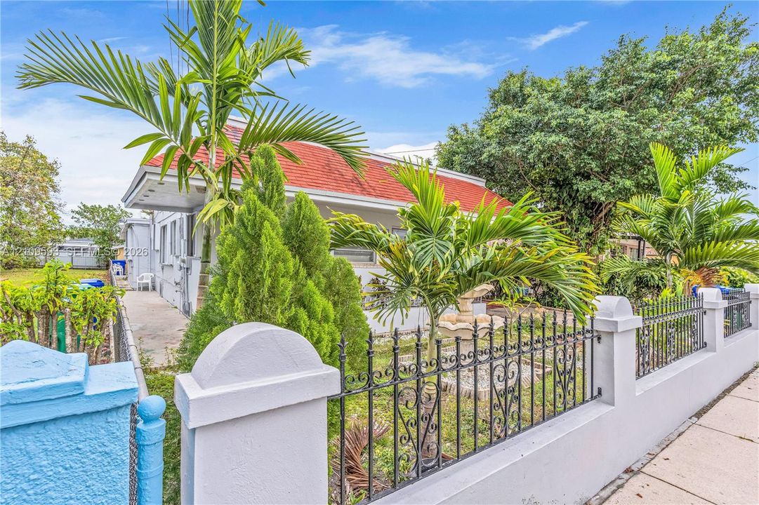 Exterior featuring a red tiled roof, a concrete masonry fence with decorative metal inserts, and mature palm landscaping