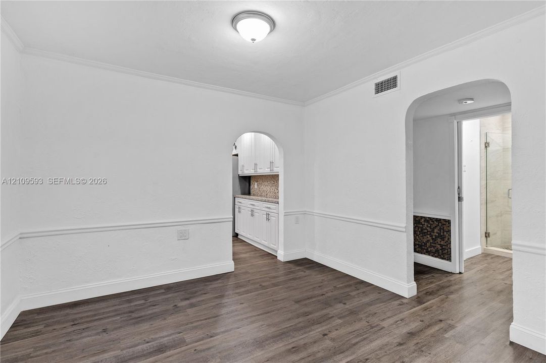 Interior space featuring wood-finish flooring, dual arched thresholds, chair rail molding, and a dome flush-mount ceiling light
