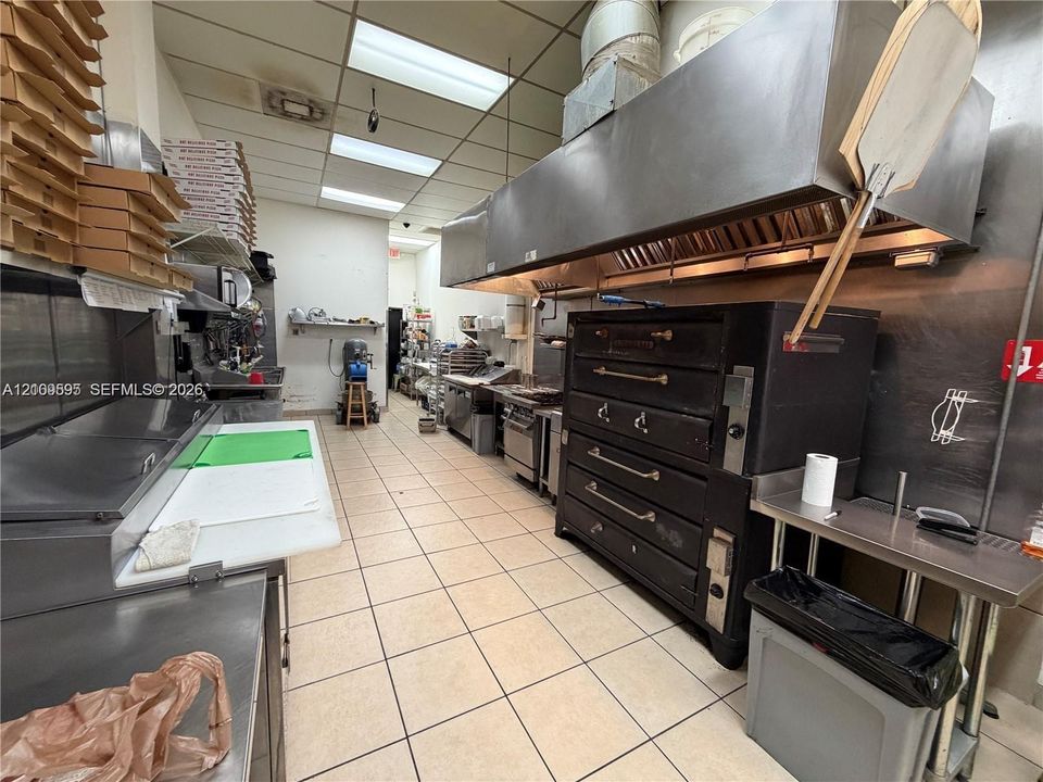 Professional Commercial Kitchen with Stainless Steel Appliances and Ventilation HoodThis fully equipped commercial kitchen features professional-grade stainless steel cooking equipment, including multiple ovens and prep stations