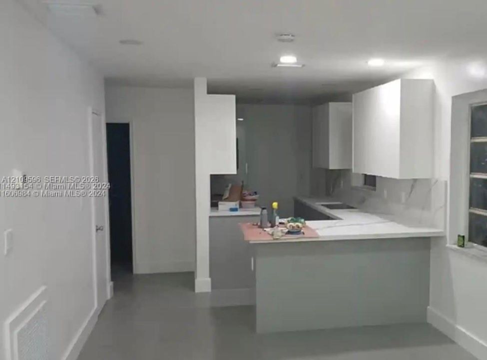 Kitchen featuring white shaker-style cabinetry, a stone-finish countertop, a peninsula breakfast bar, and recessed ceiling lighting