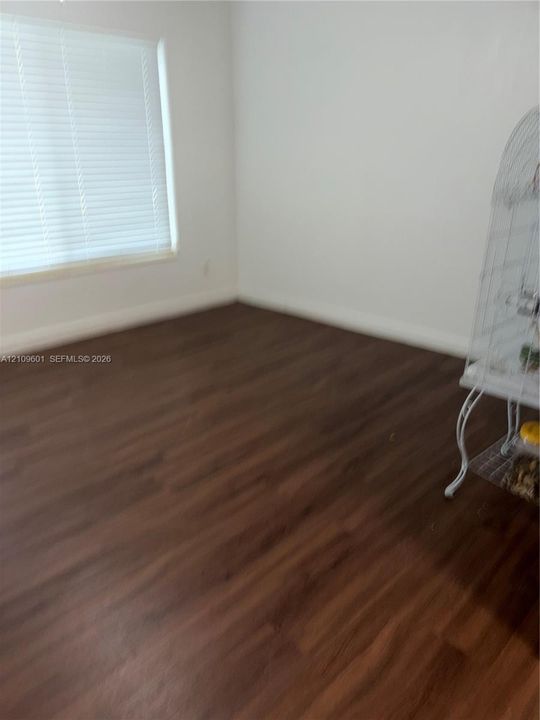 Neutral-toned walls paired with wood-finish flooring and horizontal blind window treatments