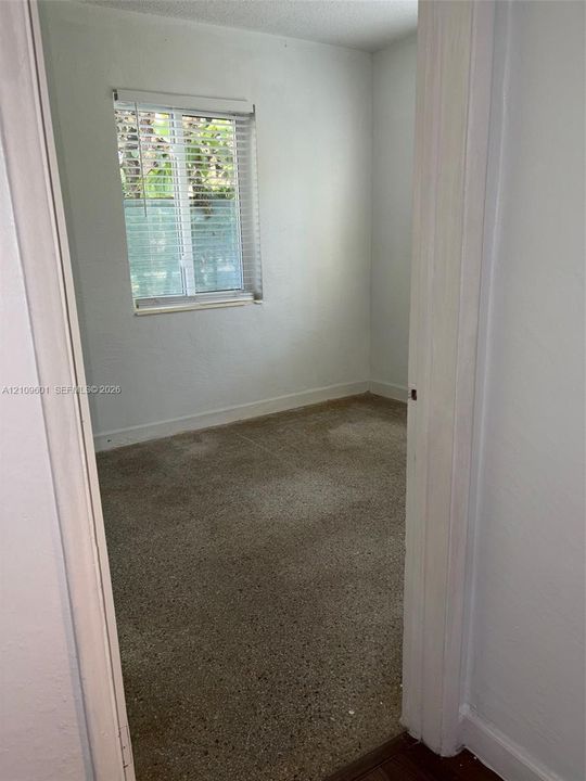 Interior space featuring neutral wall paint, terrazzo flooring, and a single-hung window with horizontal blinds