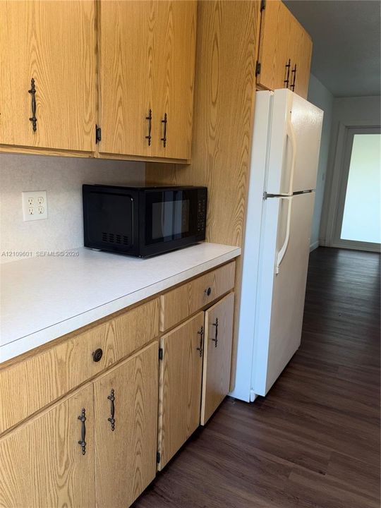 Kitchen area featuring wood-finish cabinetry, solid-surface countertops, and wood-finish flooring