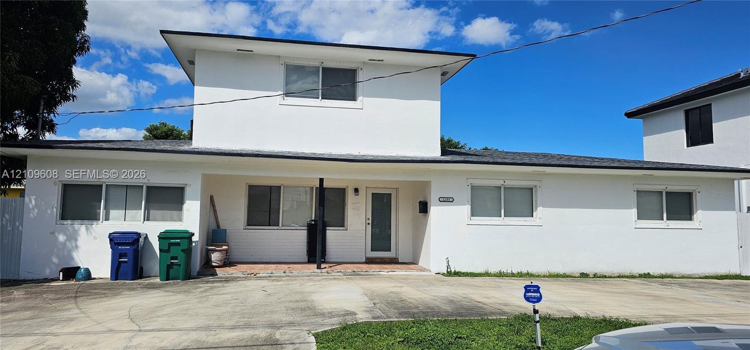 Two-story exterior featuring white stucco finish, multi-level roofline, covered entry, and concrete driveway