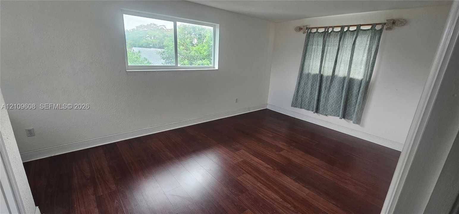 Bedroom featuring wood-finish flooring, white walls, and dual sliding windows