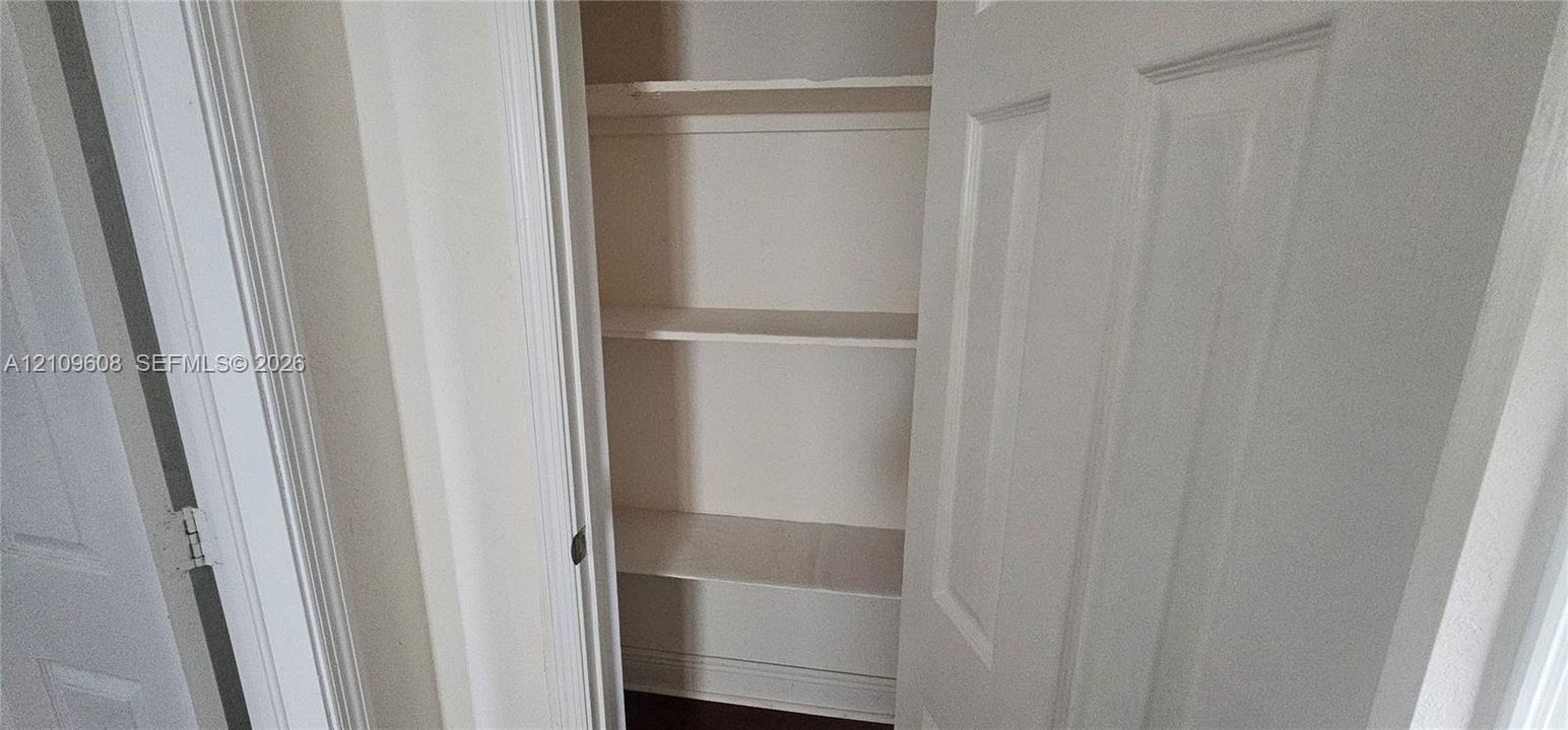 Built-in storage closet featuring multi-level shelving and a white paneled door