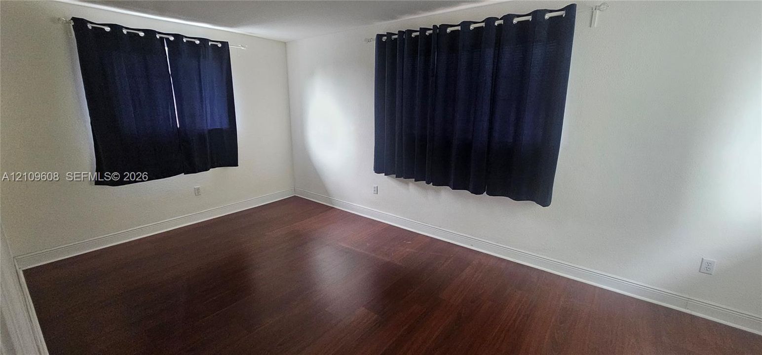 Interior room featuring wood-finish flooring, white walls, and multiple windows