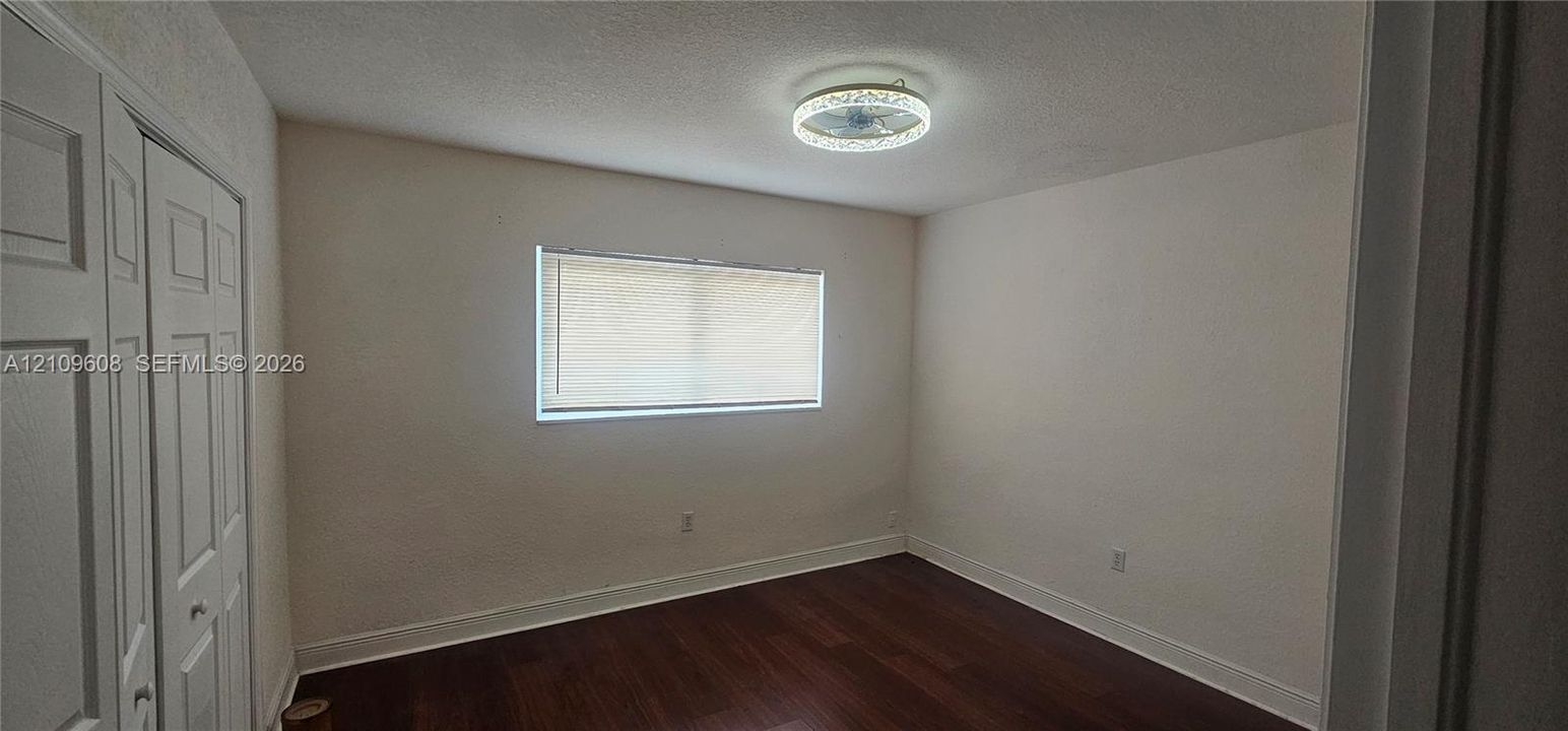 Room featuring wood-finish flooring, dual-panel closet doors, and a circular LED flush-mount light fixture