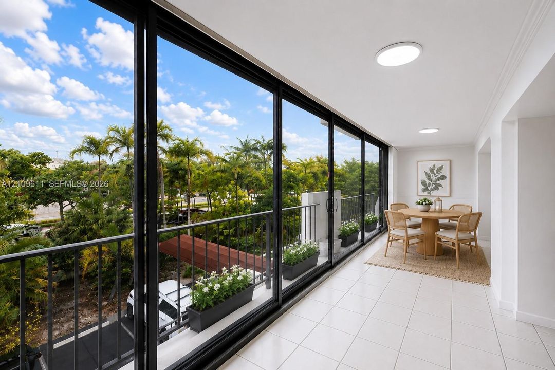 Covered balcony featuring floor-to-ceiling black-framed sliding glass doors, white tile flooring, and black metal railings