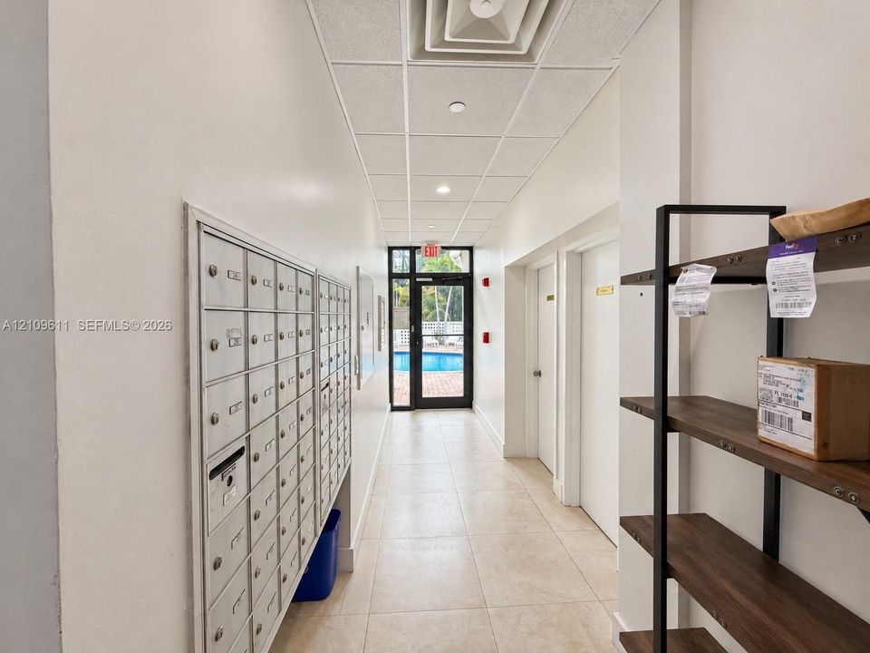 Hallway featuring tile flooring, a drop ceiling, and integrated postal boxes
