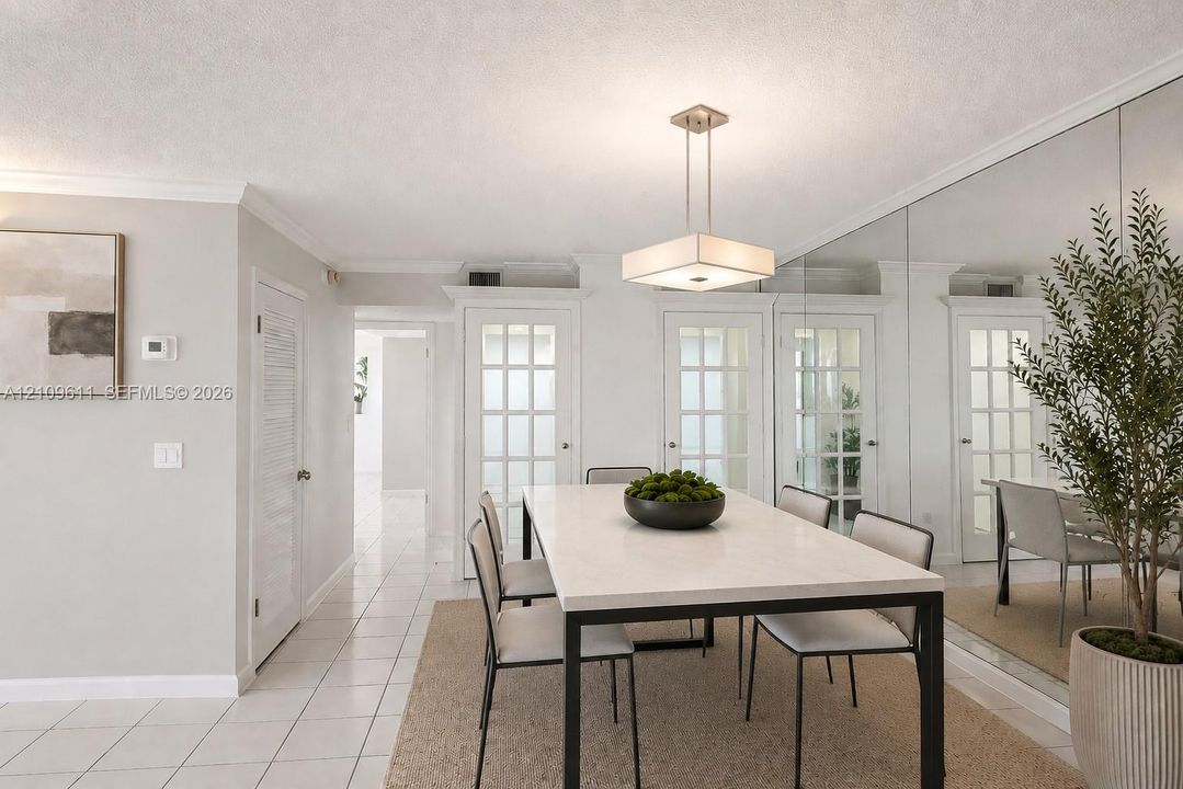 Dining space featuring floor-to-ceiling mirrored walls, a square brushed-nickel pendant light, and triple French doors with glass panes