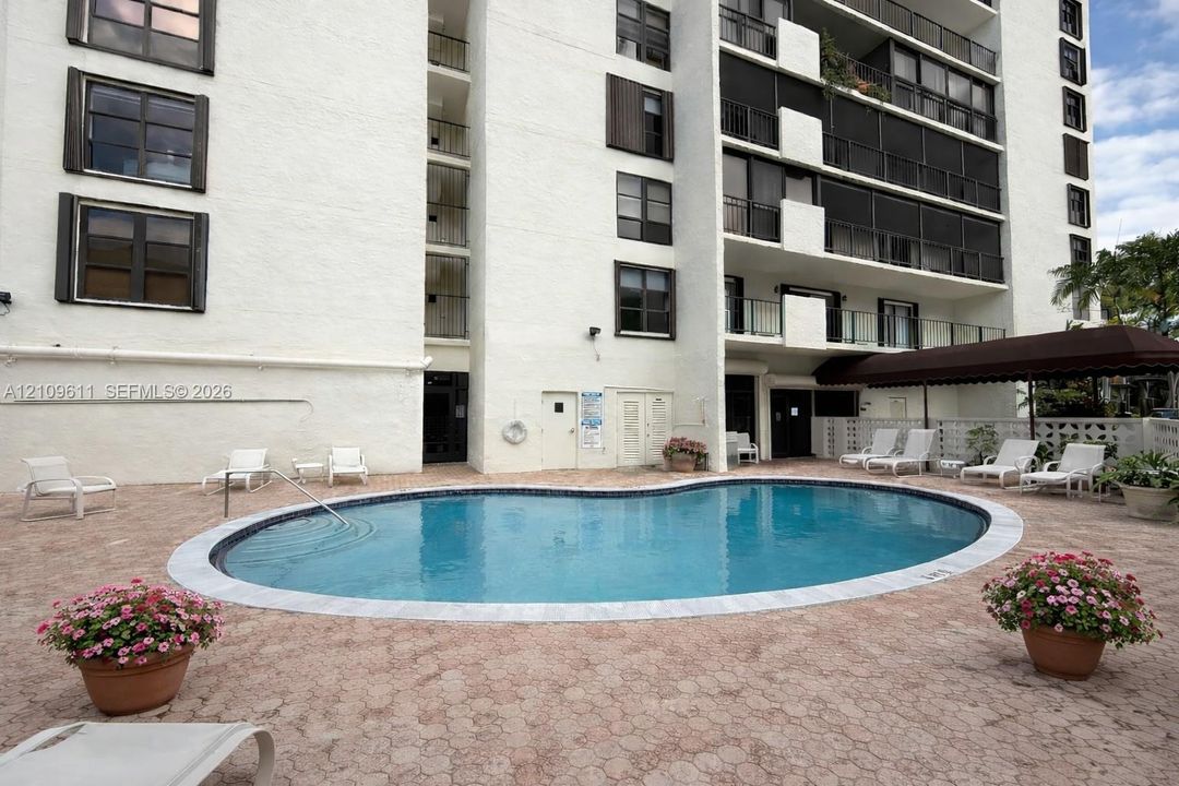 Community swimming pool featuring a curved concrete deck, integrated pool entry rail, and shaded patio area
