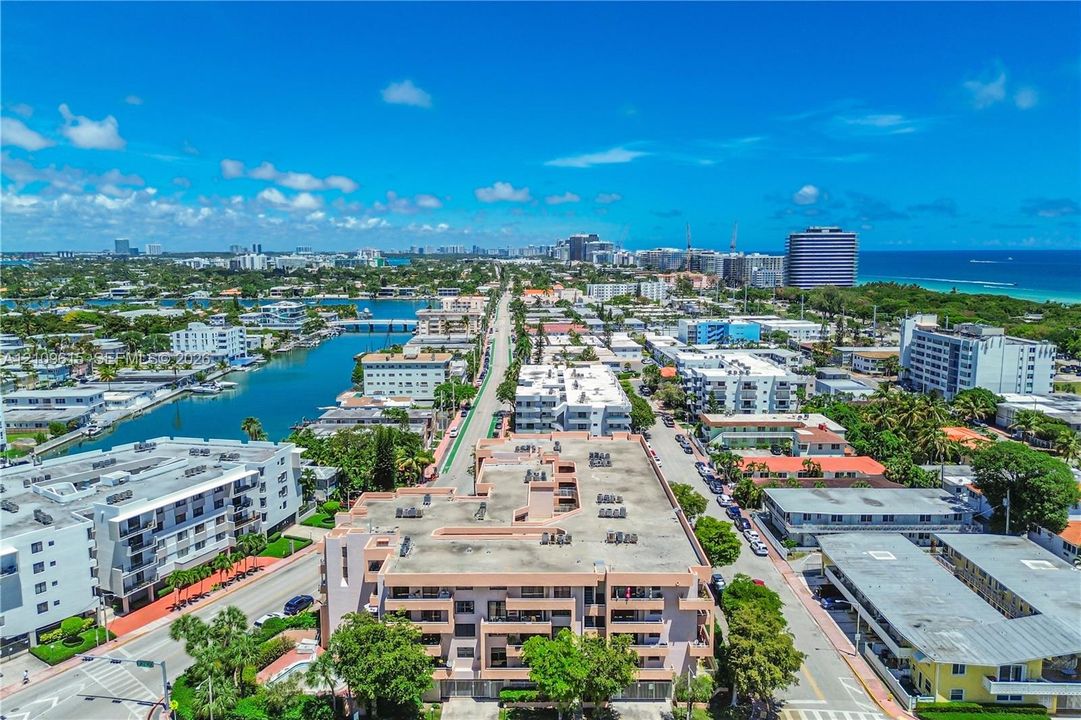 Aerial perspective of a multi-story residential building located within a coastal neighborhood featuring waterways and oceanfront proximity