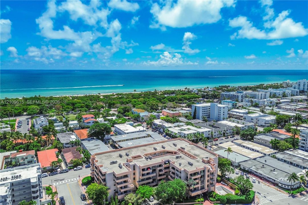 Aerial perspective of a multi-story residential building featuring private recessed balconies and proximity to the coastline