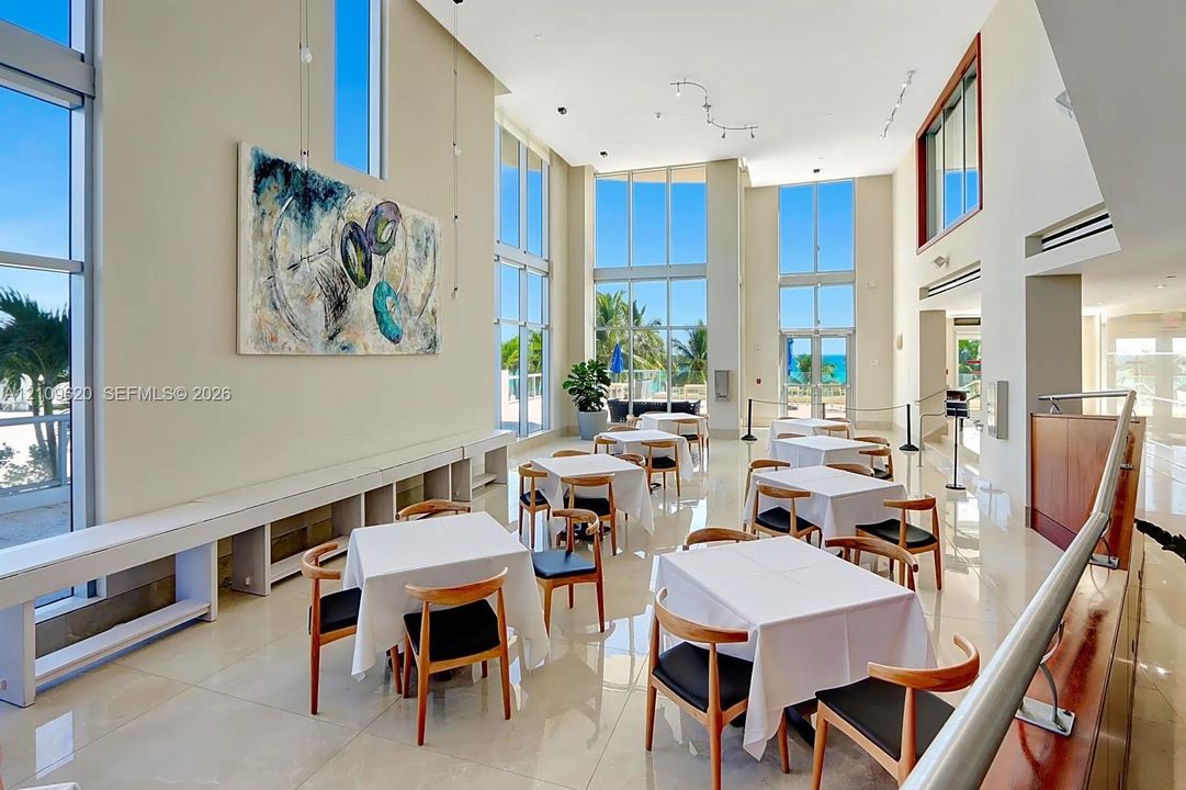 Expansive common area featuring floor-to-ceiling windows, soaring vaulted ceilings, polished tile flooring, and custom built-in bench seating
