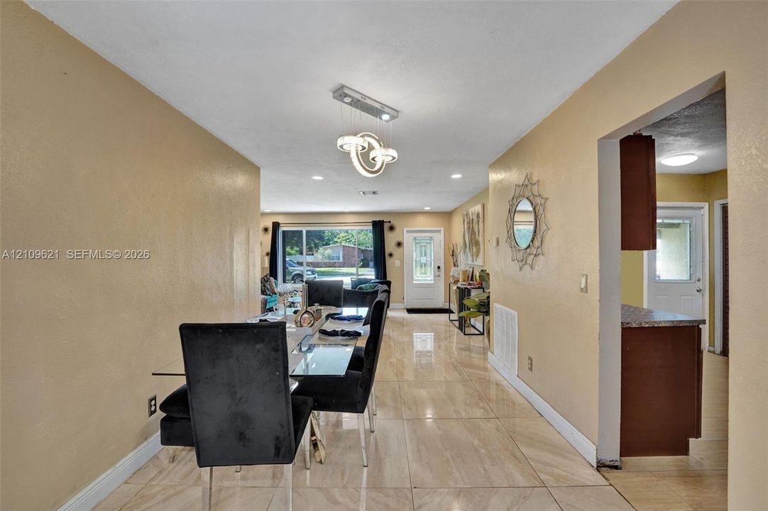 Large-format stone-style tile flooring, decorative multi-ring pendant light fixture, and recessed ceiling lighting