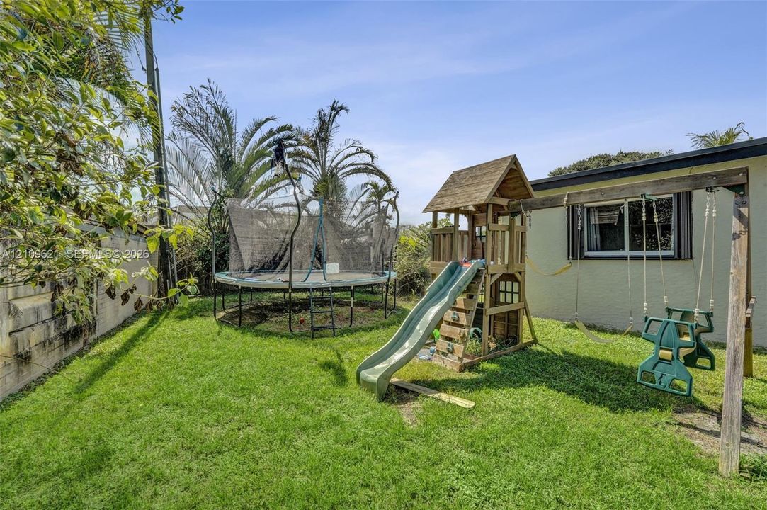Fenced backyard featuring a manicured lawn, masonry perimeter wall, and mature palm trees